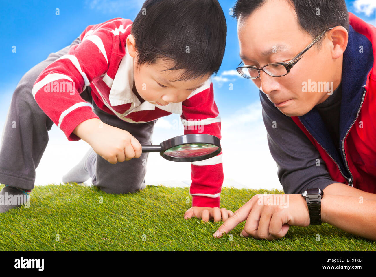 father and kid with magnifying glass to discover in the grassland Stock Photo