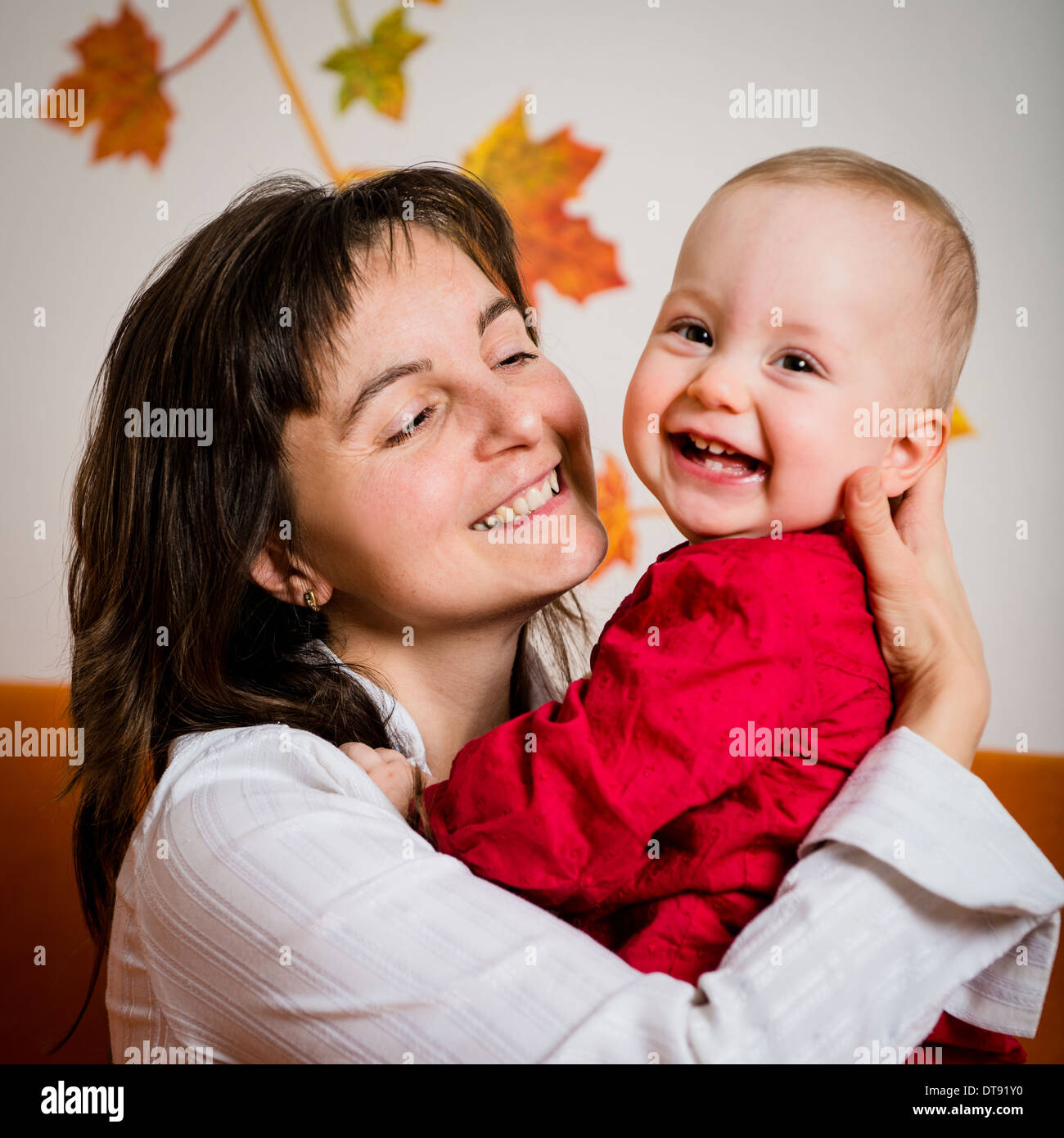 Portrait of young smiling mother with her happy baby - indoor Stock Photo