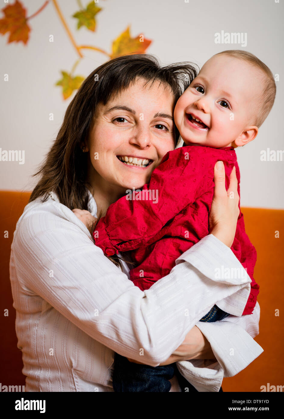 Portrait of young smiling mother with her happy baby - indoor Stock Photo