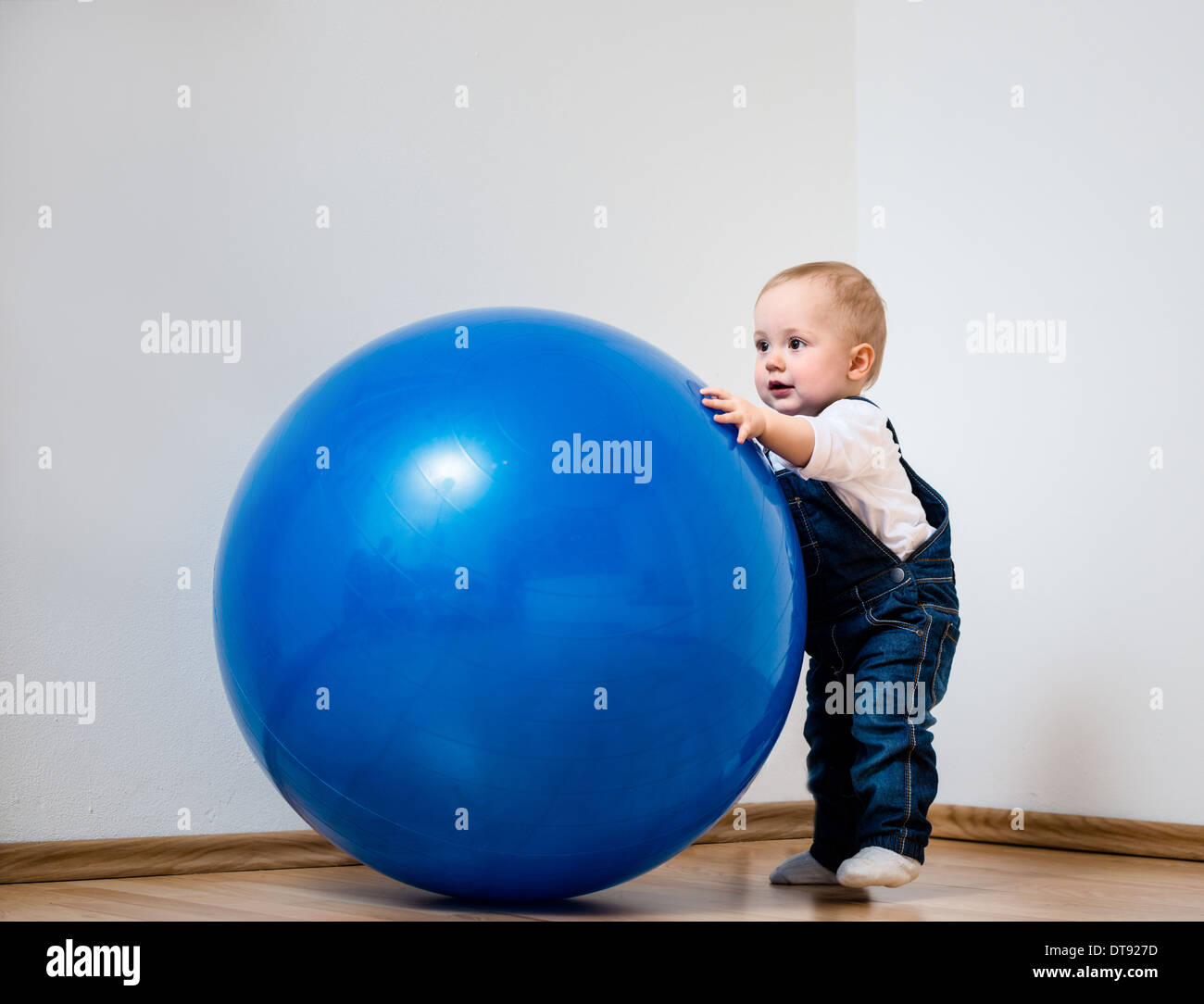 Little baby is playing with big blue fit ball at home Stock Photo