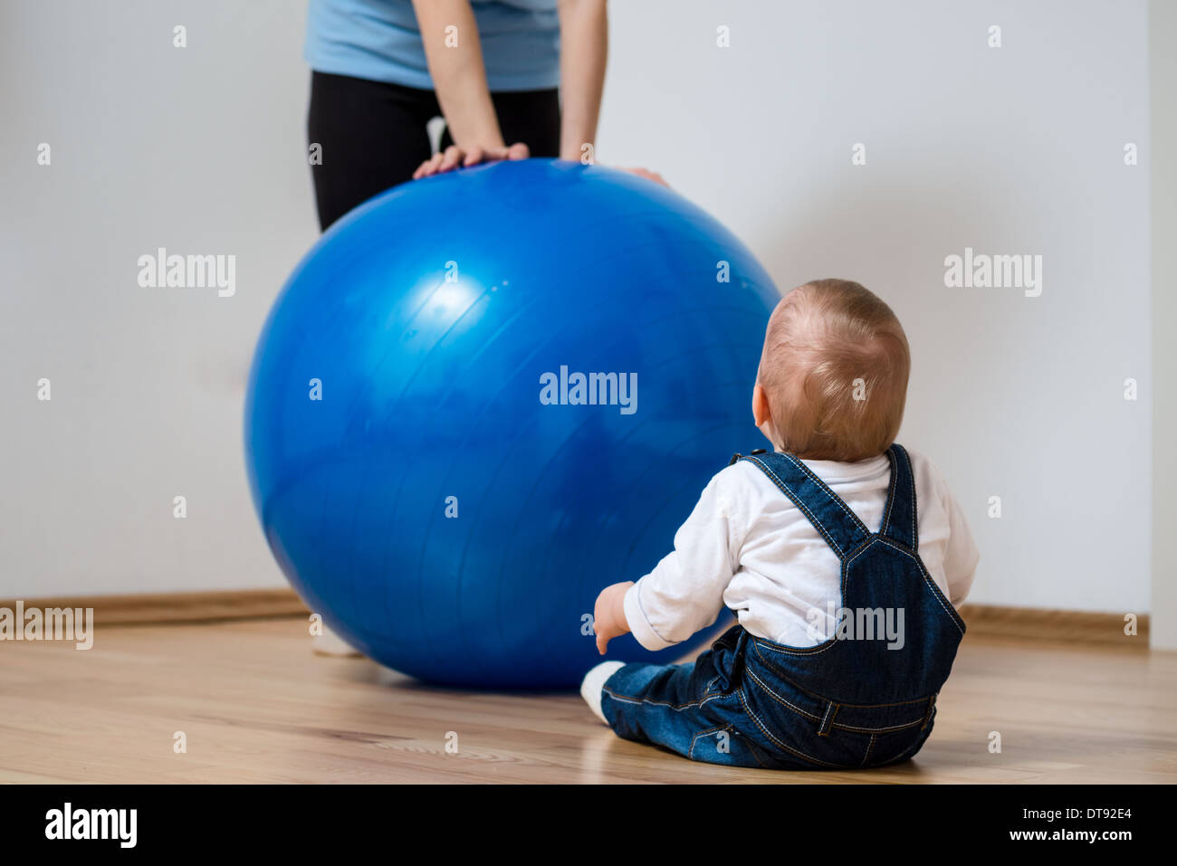 Mother exercises with big blue fit ball and baby - home interior Stock Photo