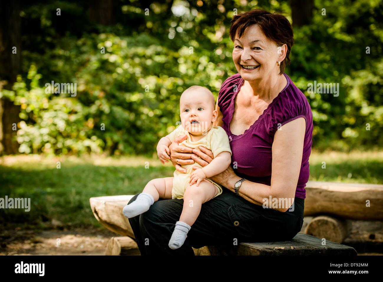 Grandmother with grandchild - senior woman sitting with her granddaughter on bench outdoor in nature Stock Photo