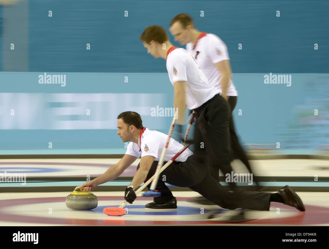 David Murdoch (GBR, skip) pushes off with Michael Goodfellow (GBR, right) and Scott Andrews (GBR). Mens curling - Ice Cube Curling Centre - Olympic Park - Sochi - Russia - 12/02/2014 Stock Photo