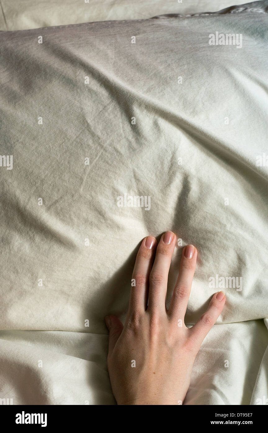 A manicured hand toughing a bed Stock Photo