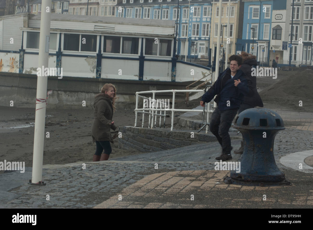 Aberystwyth, Wales, UK. 12th Feb, 2014. Aberystwyth University students, struggling against the high winds on Aberystwyth prom. Stock Photo