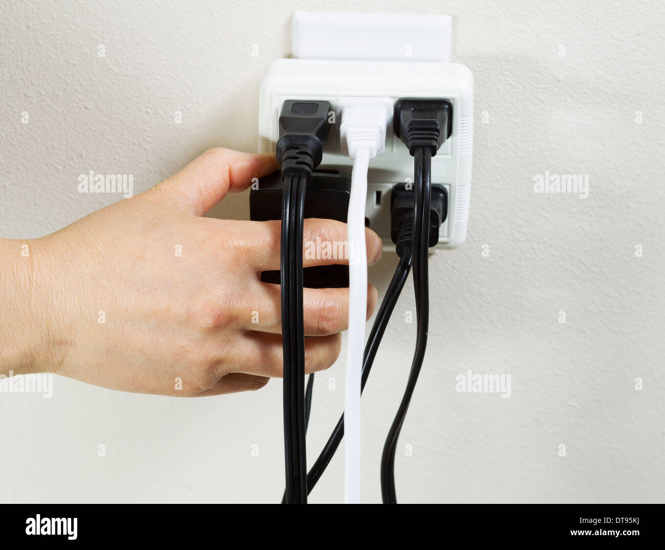 Photo of female hand plugging in power adapter into multiple electrical wall unit outlets Stock Photo