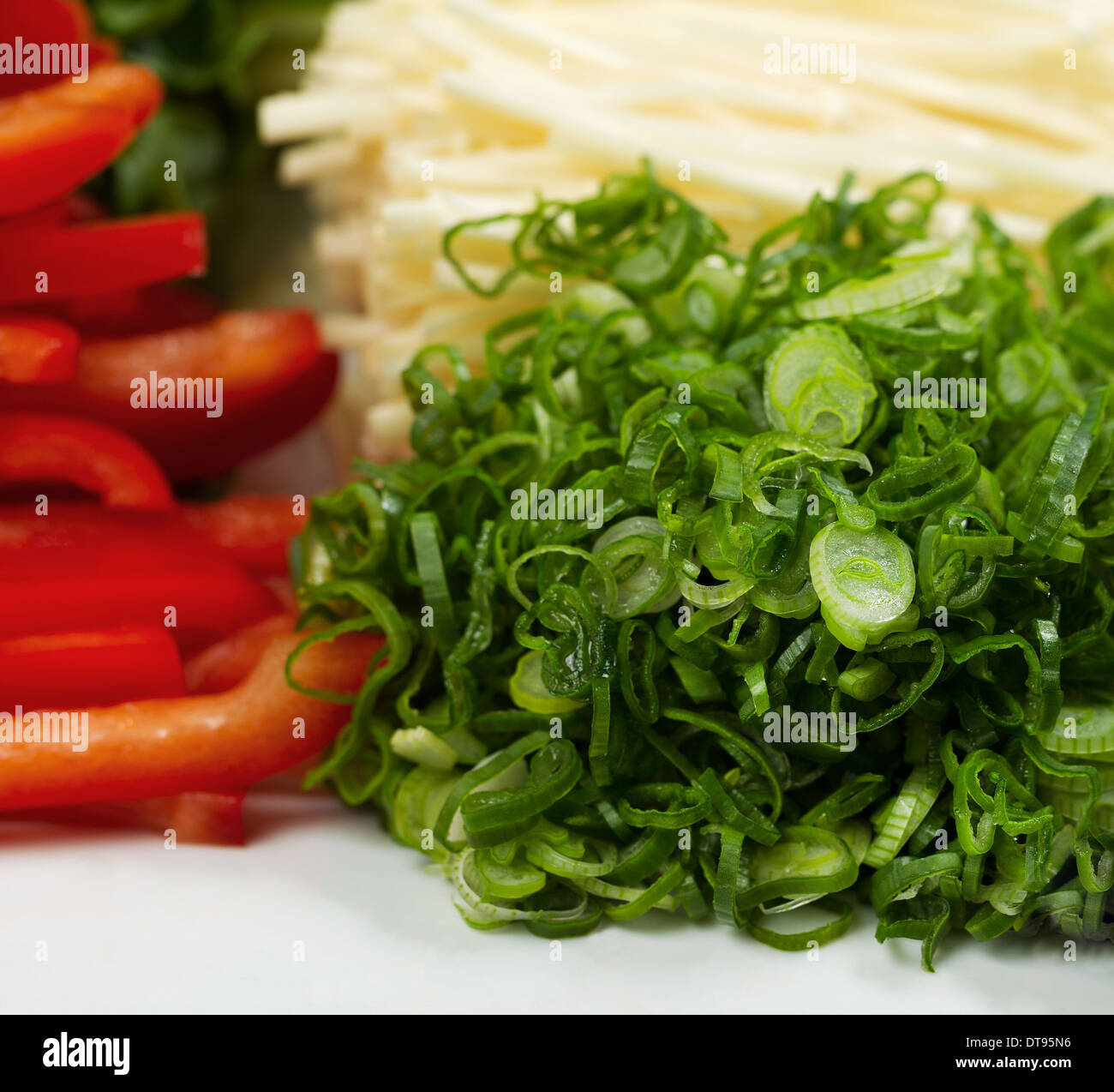 Closeup photo of fresh sliced green onions used as sushi ingredients placed in white plate along with mushrooms and red peppers Stock Photo