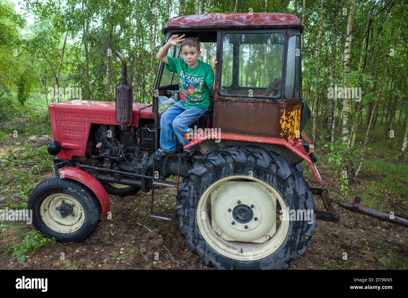 Boy age 8 waving from doorway of small Polish farm tractor. Zawady Central Poland Stock Photo