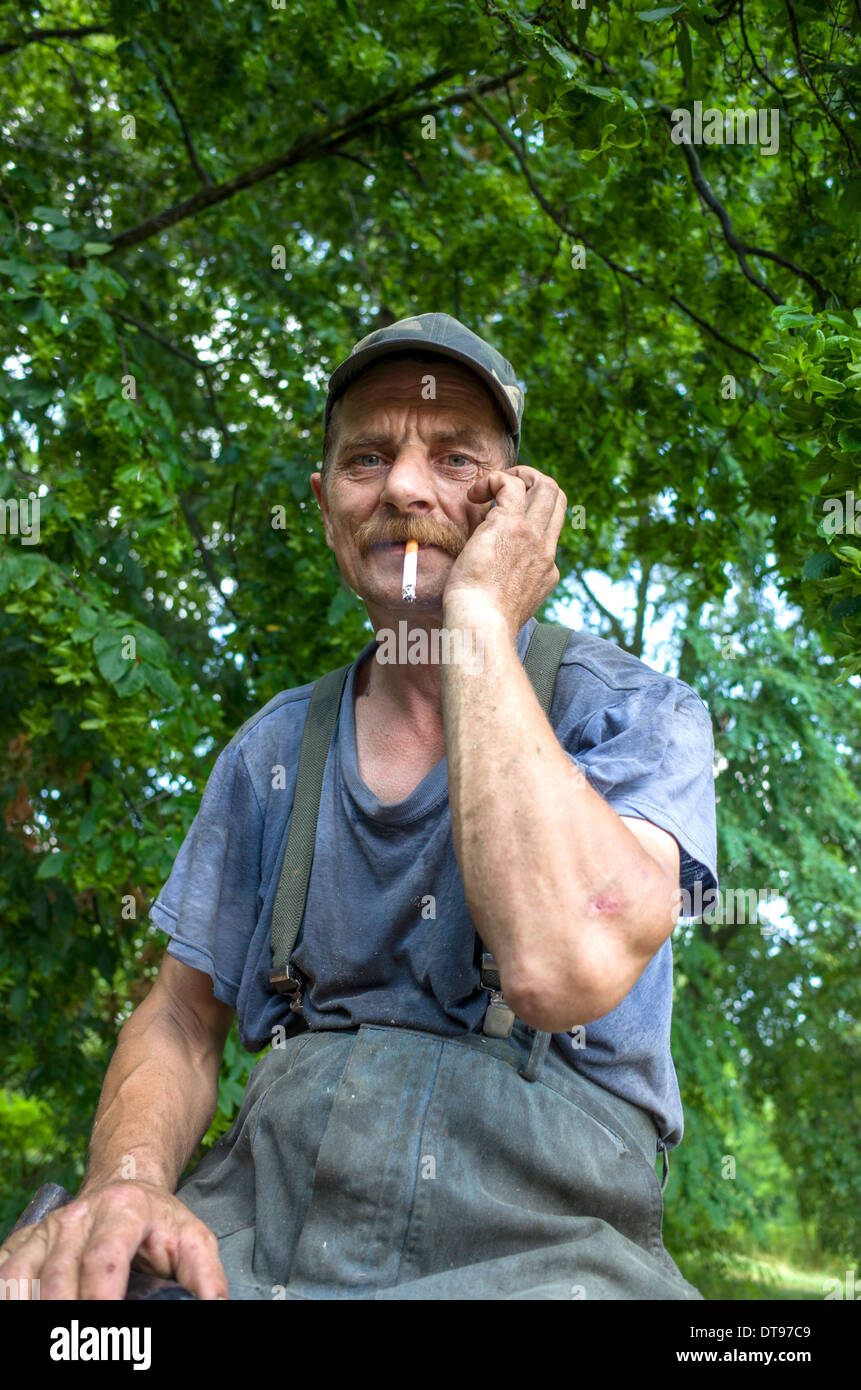 Polish farmer in his work clothes taking a smoke break. Zawady Central Poland Stock Photo