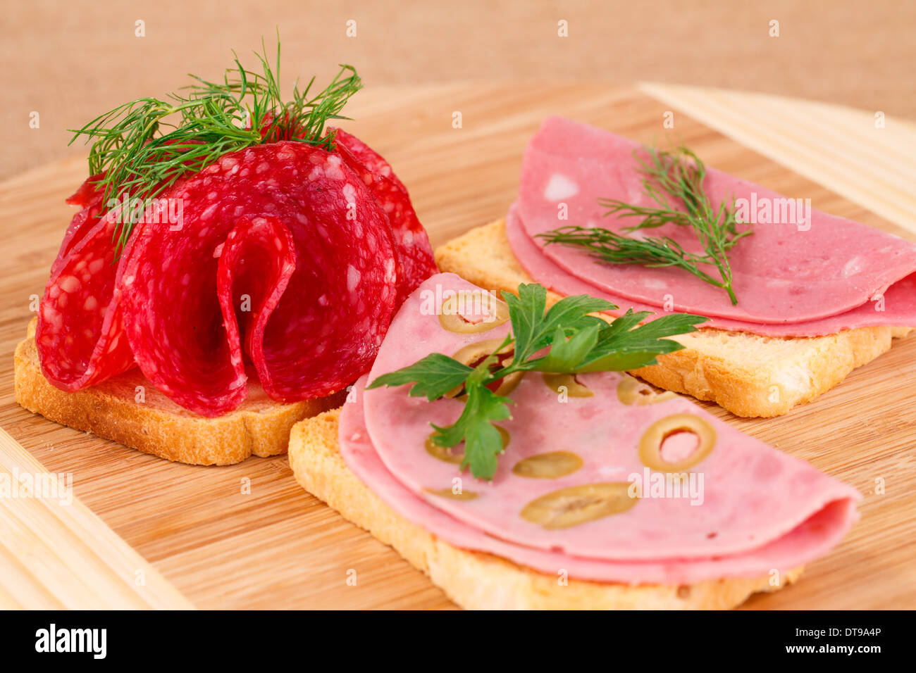 Sandwiches with salami and mortadella on wooden board. Stock Photo