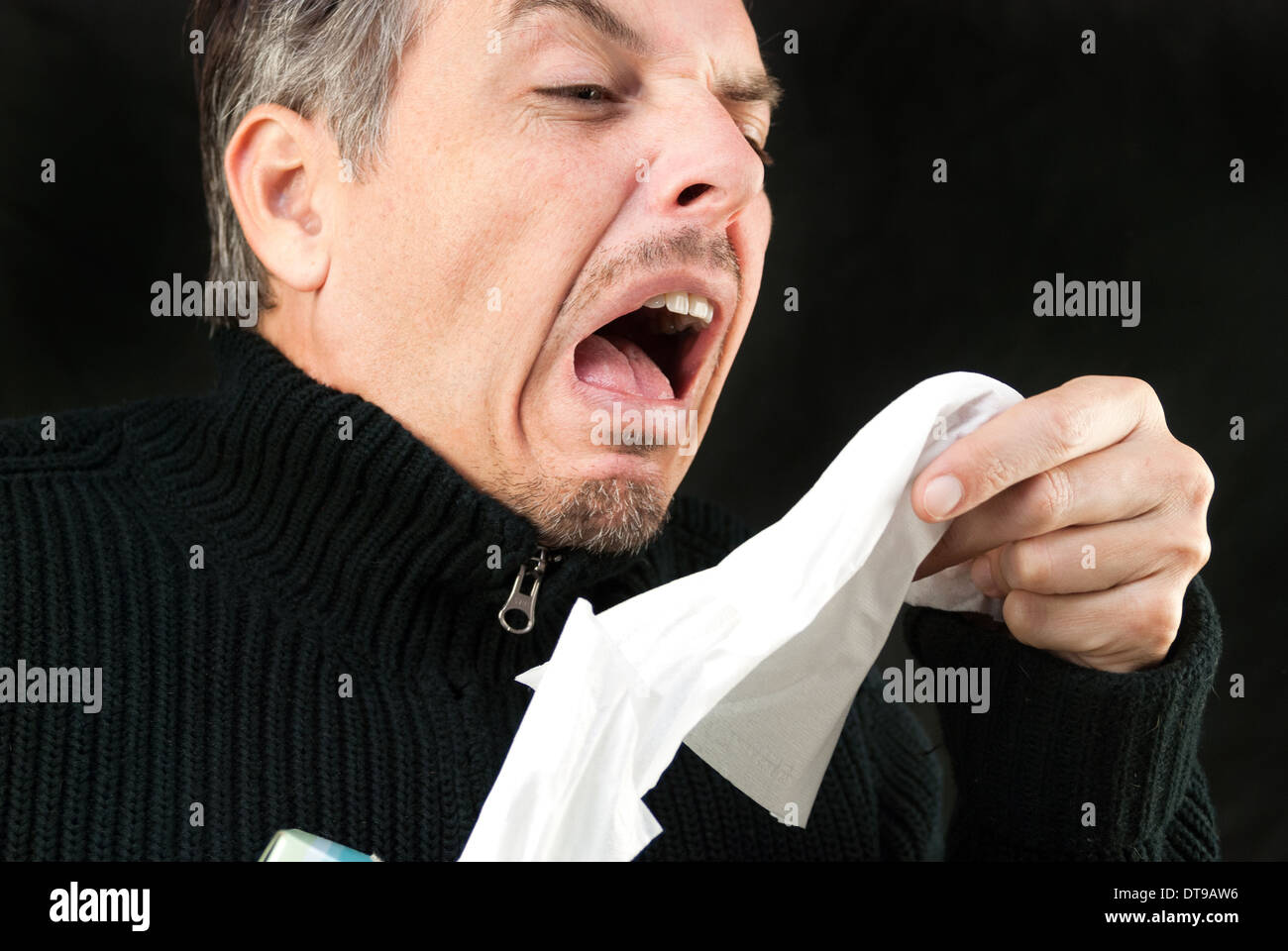 Close-up of a man sneezing while pulling a tissue out of the box. Stock Photo