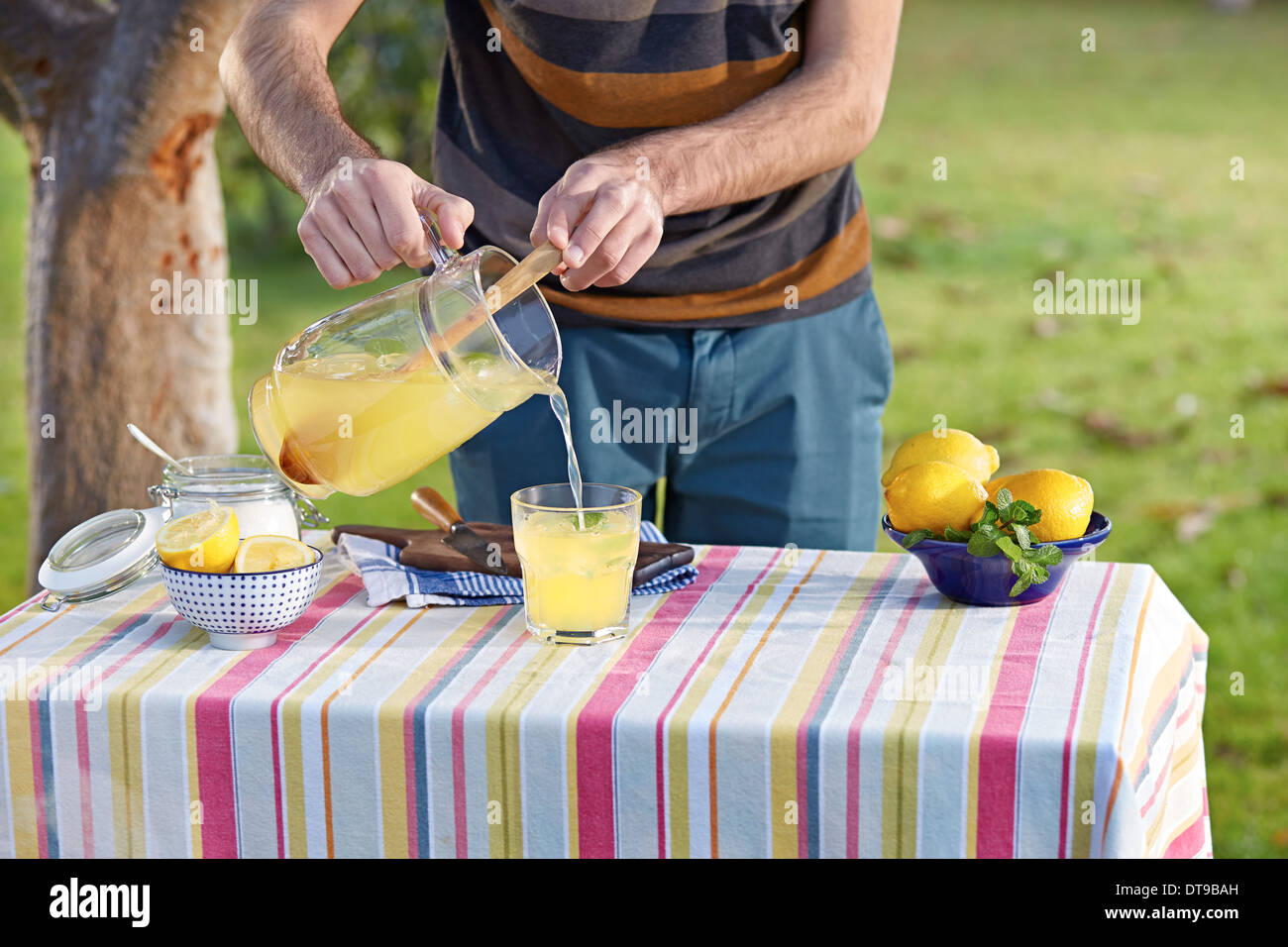 Pouring homemade lemonade in glass at garden table Stock Photo