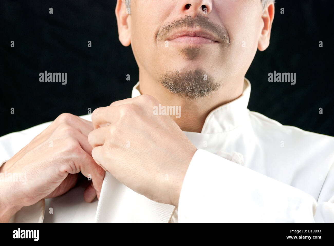 Close-up of a chef doing up his jacket. Stock Photo