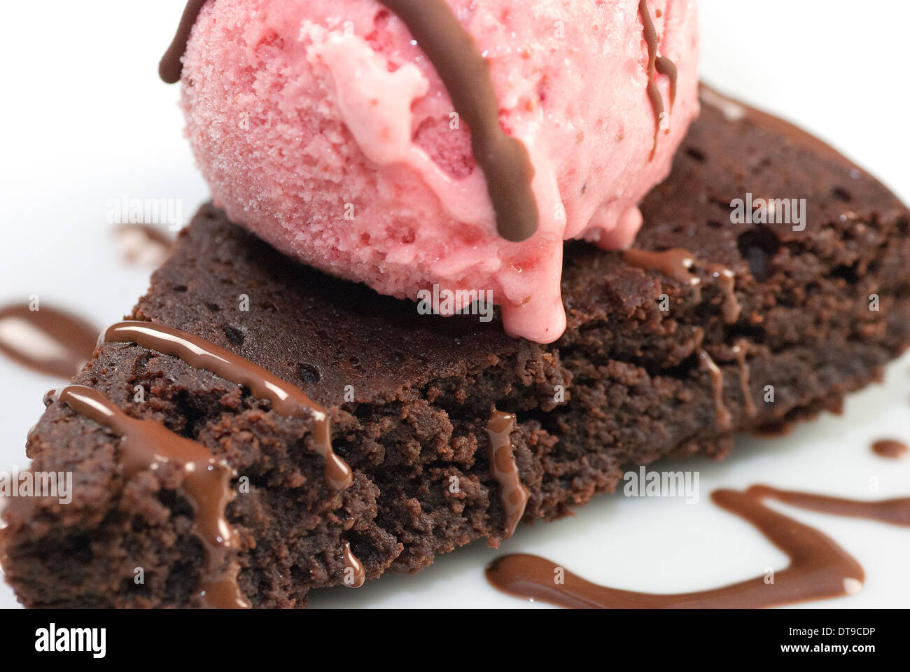 Close-up of a brownie with raspberry ice cream and a white chocolate garnish. Stock Photo