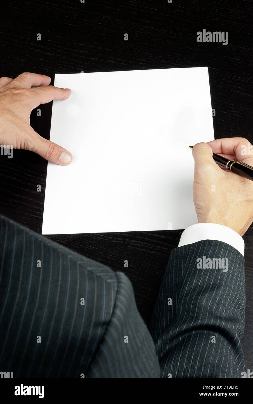 Close-up of a businessman writing, shot from over the shoulder. Stock Photo