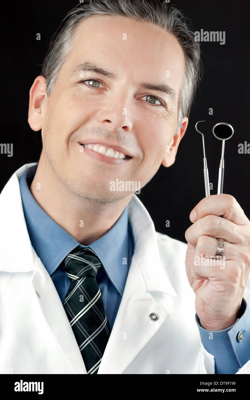Close-up of a smiling dentist holding his tools Stock Photo