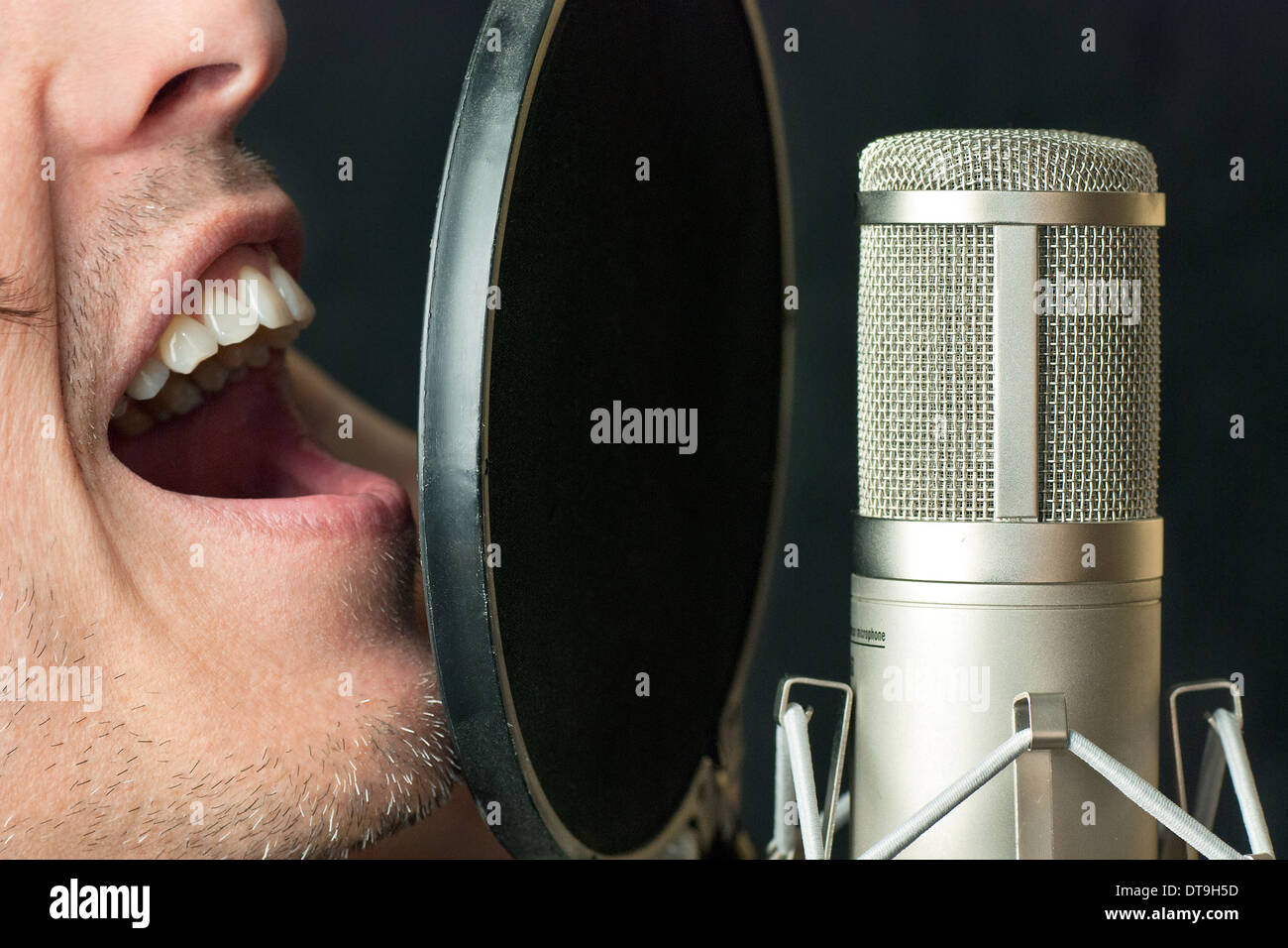Super close-up of a man singing into a condenser microphone Stock Photo