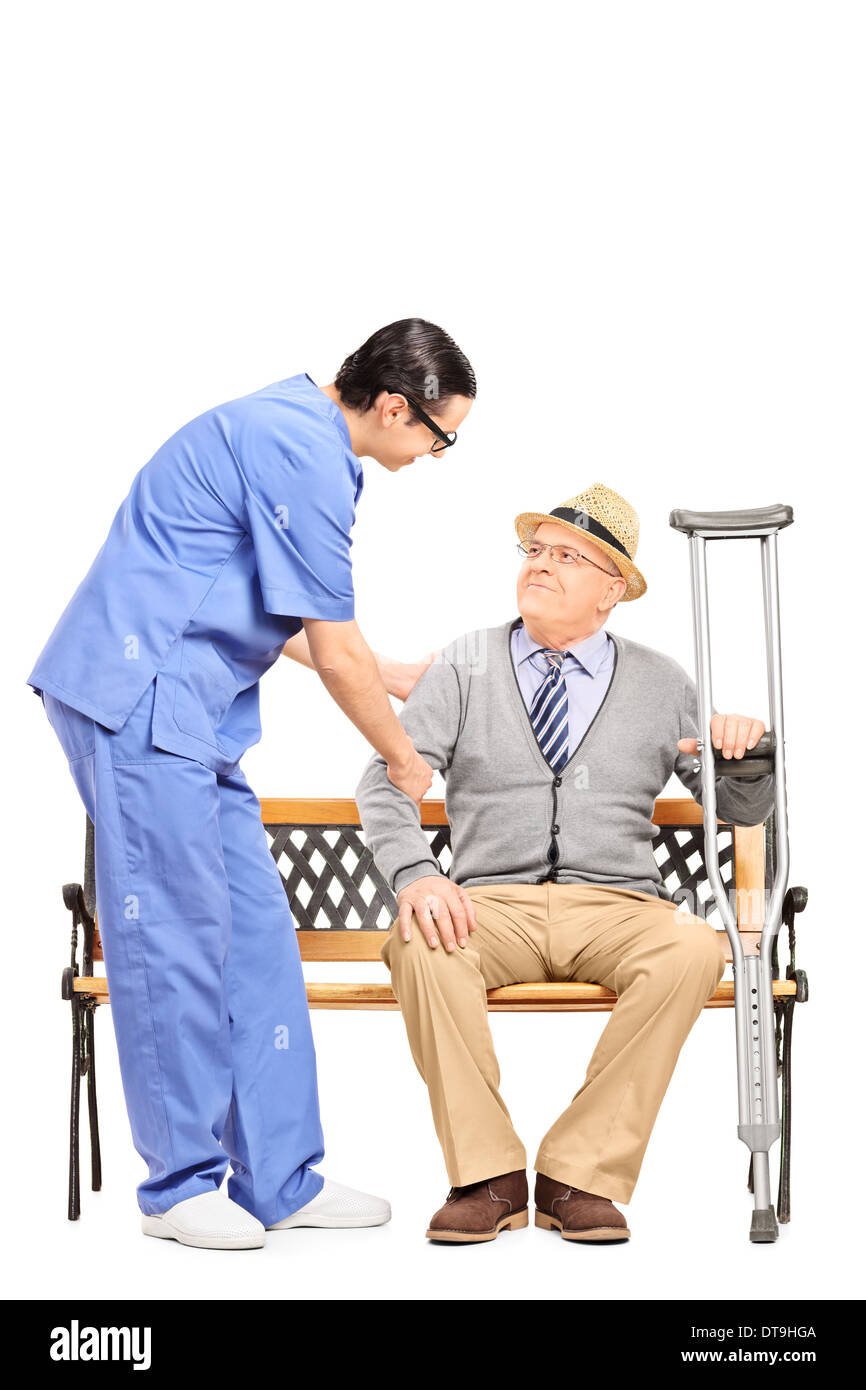 Male healthcare professional assisting a senior gentleman seated on bench Stock Photo