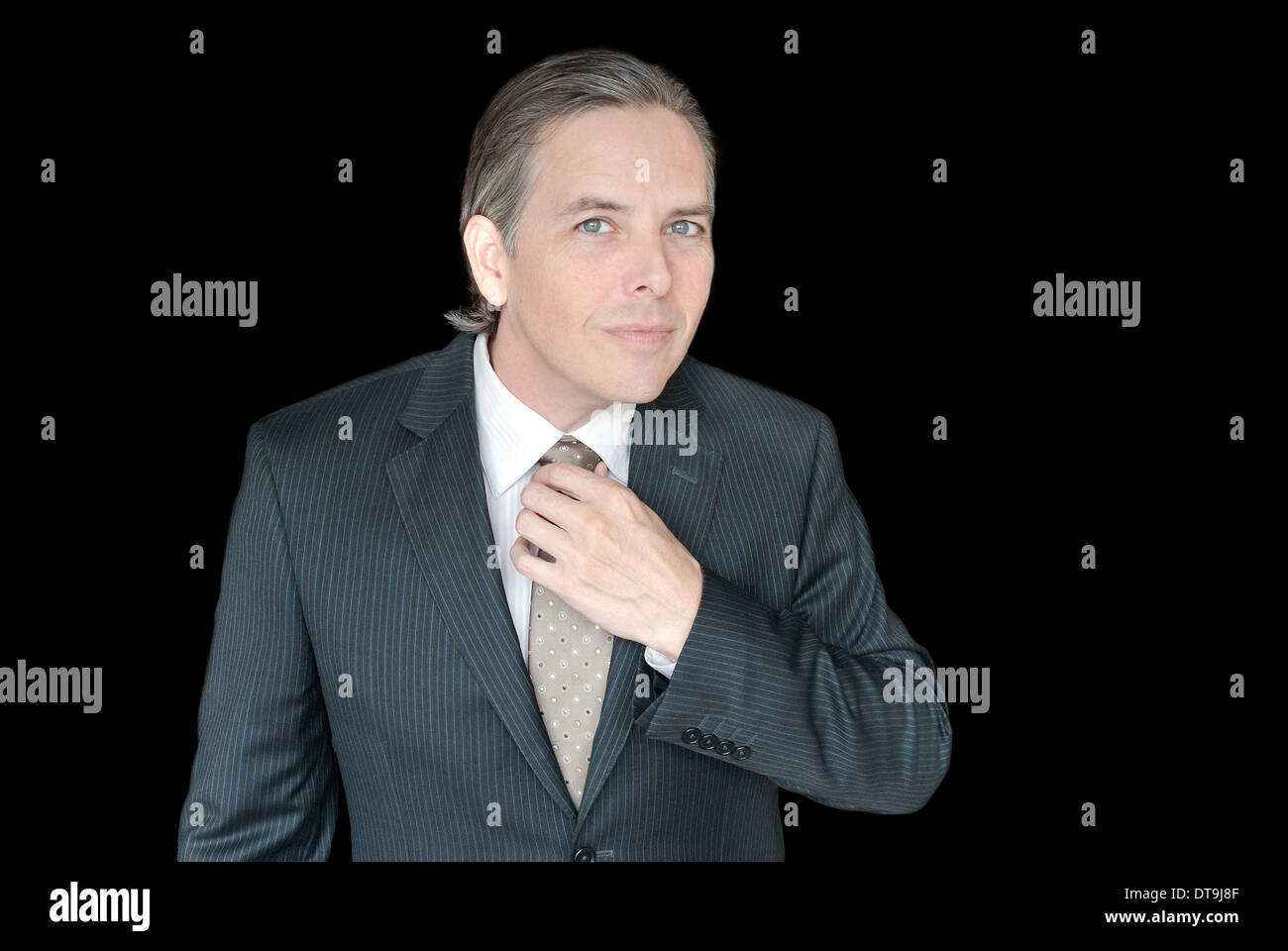 Close-up of a businessman adjusting his tie, waist-up. Stock Photo