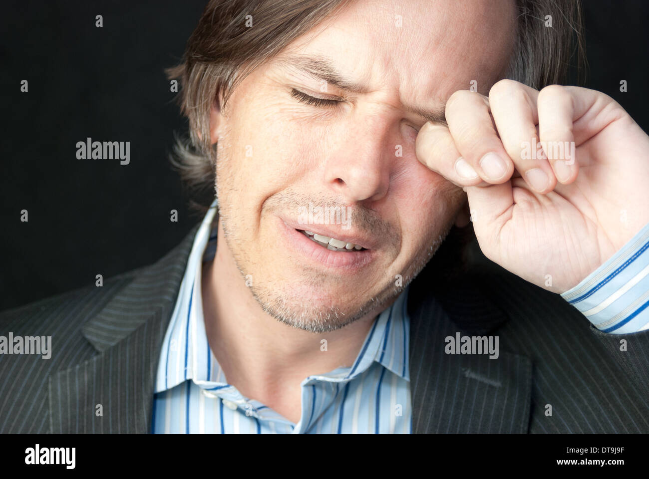 Close-up of a stressed businessman rubbing his eyes. Stock Photo