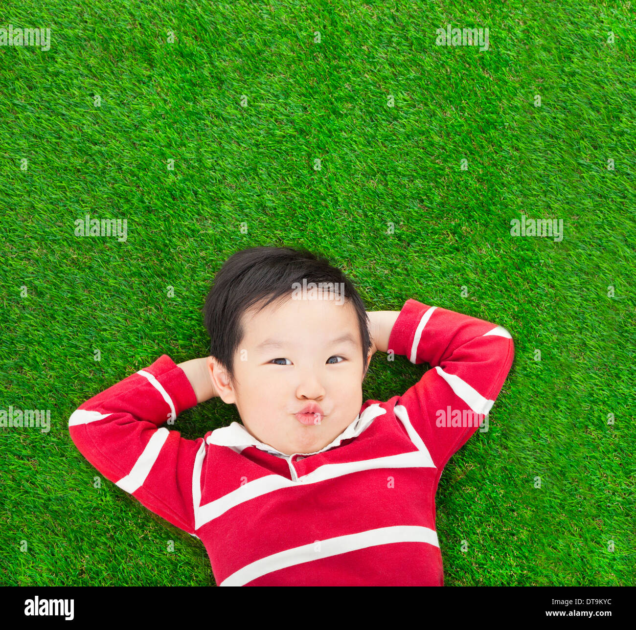 A funny kid lying and holding his head on meadow Stock Photo