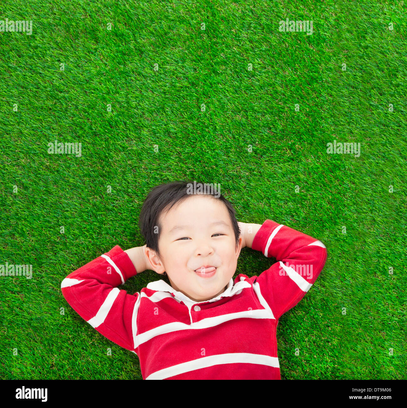 A spoof expression kid lying and holding his head on meadow Stock Photo