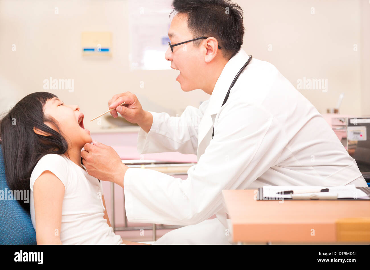 Little girl having throat examination with tongue depressor in clinic Stock Photo