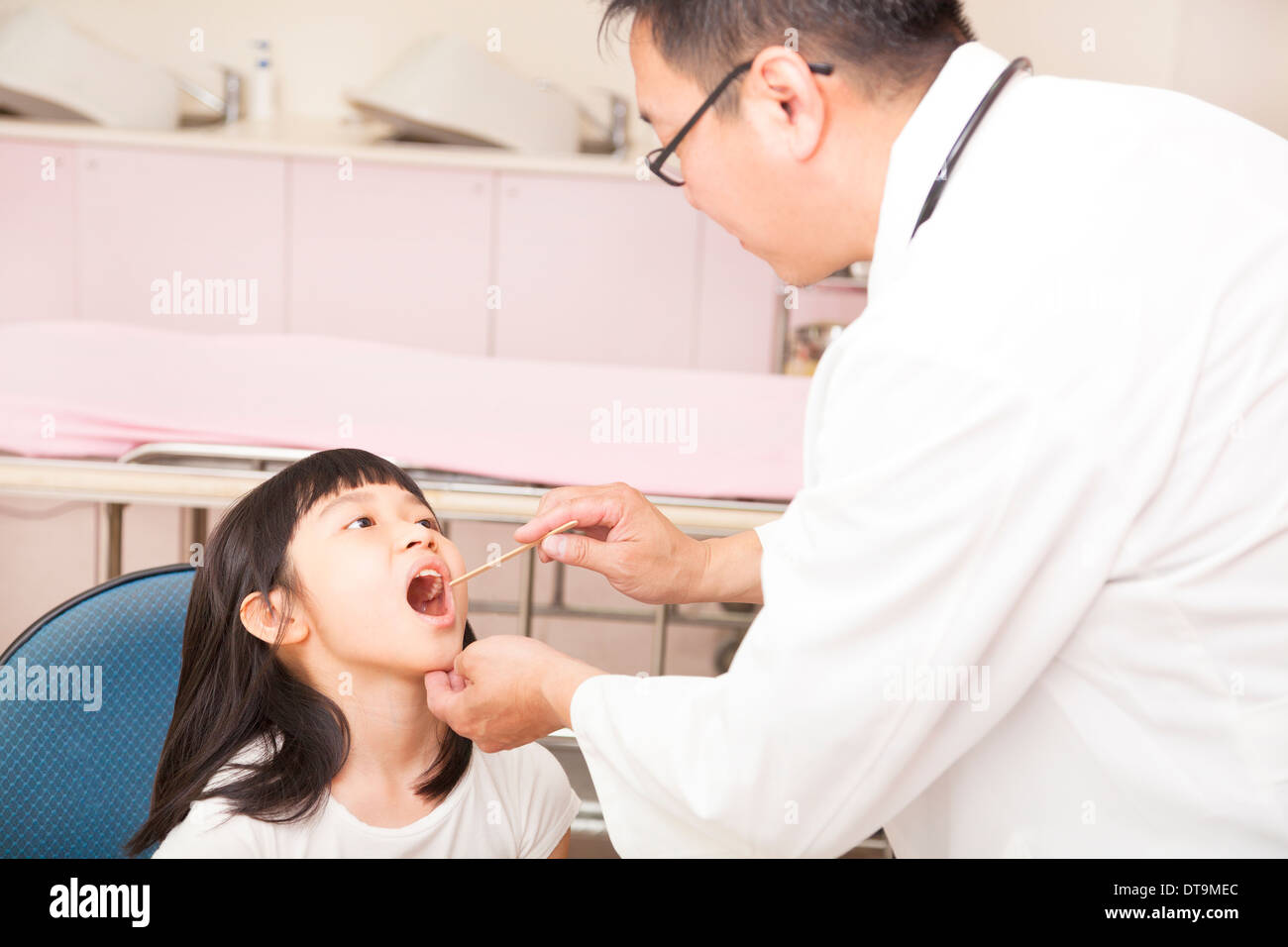 pediatrician examining  kid throat with  tongue depressor in clinic Stock Photo