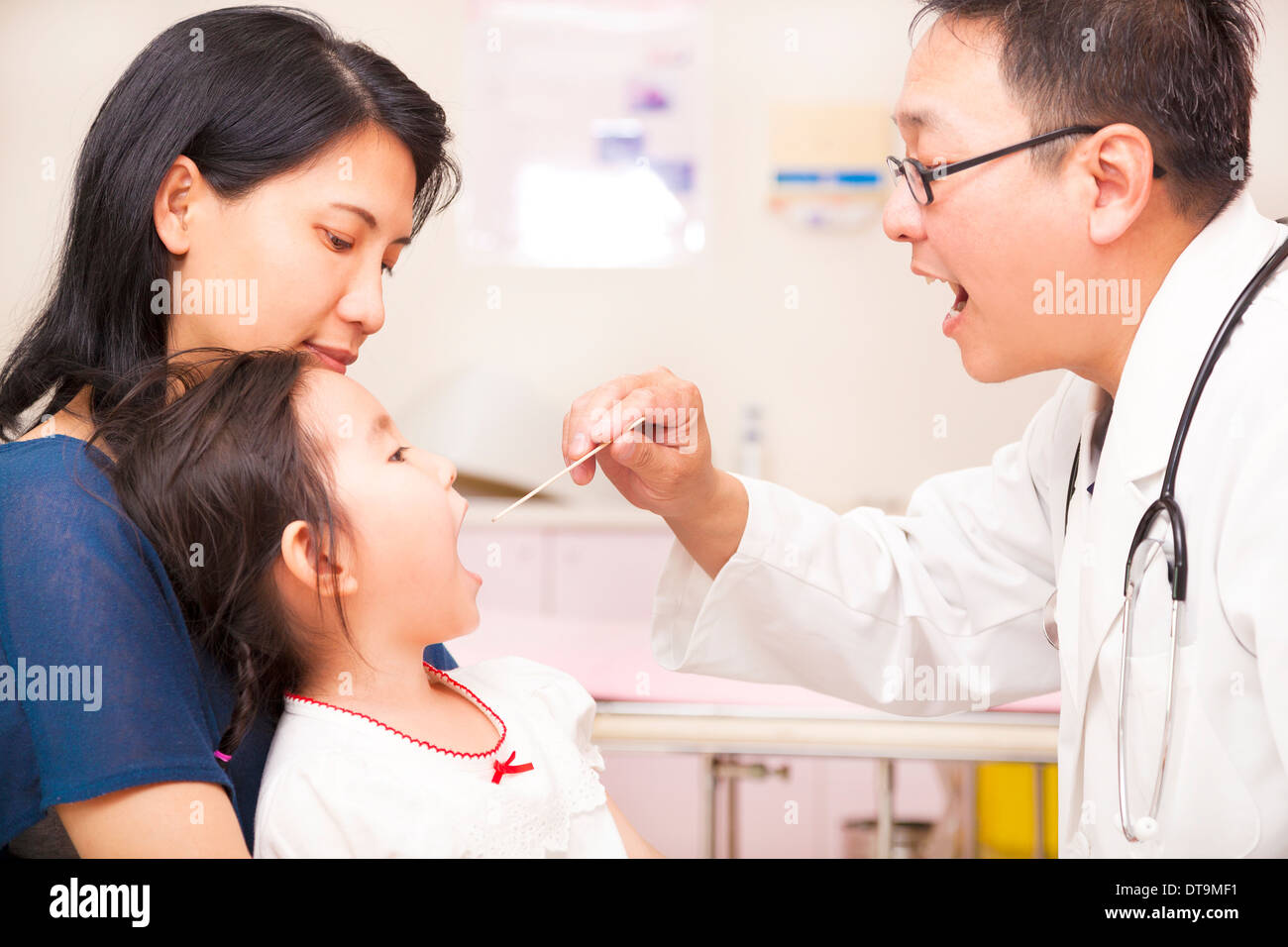Pediatrician checking little girl throat in clinic Stock Photo