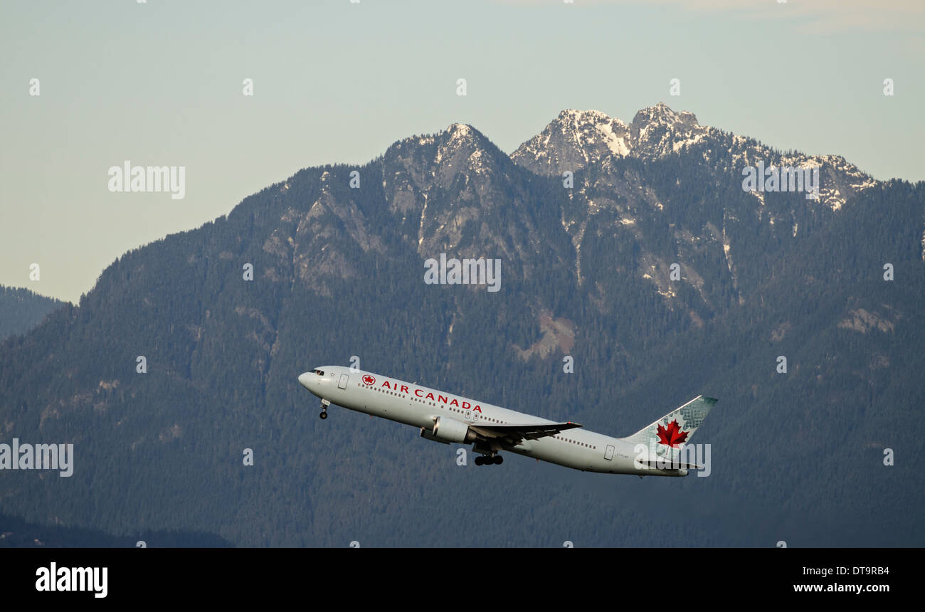 An Air Canada Boeing 767  wide-body jetliner departs from Vancouver International Airport scenic mountain view as background Stock Photo