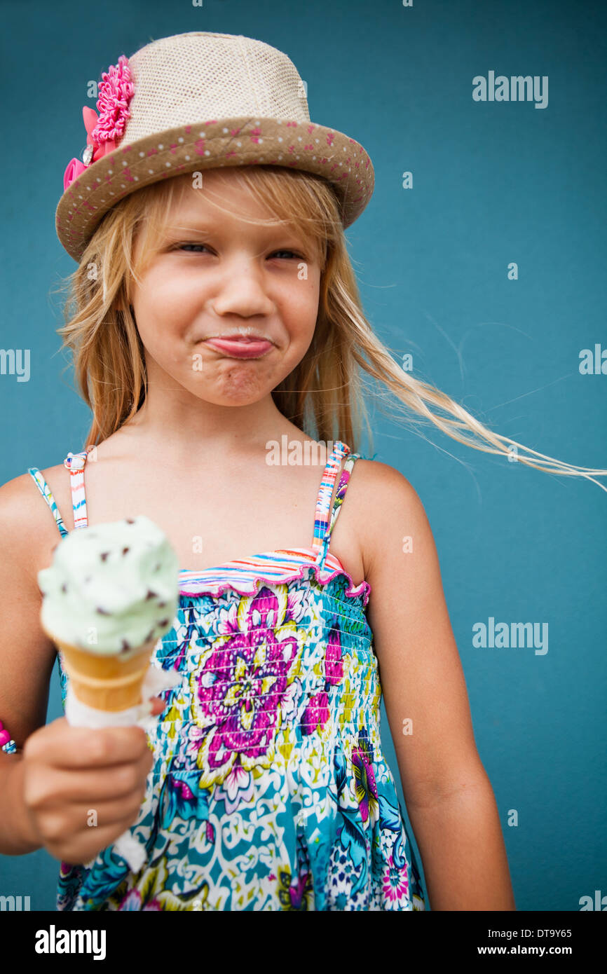 Cute young girl with funny expression holding ice cream cone outside