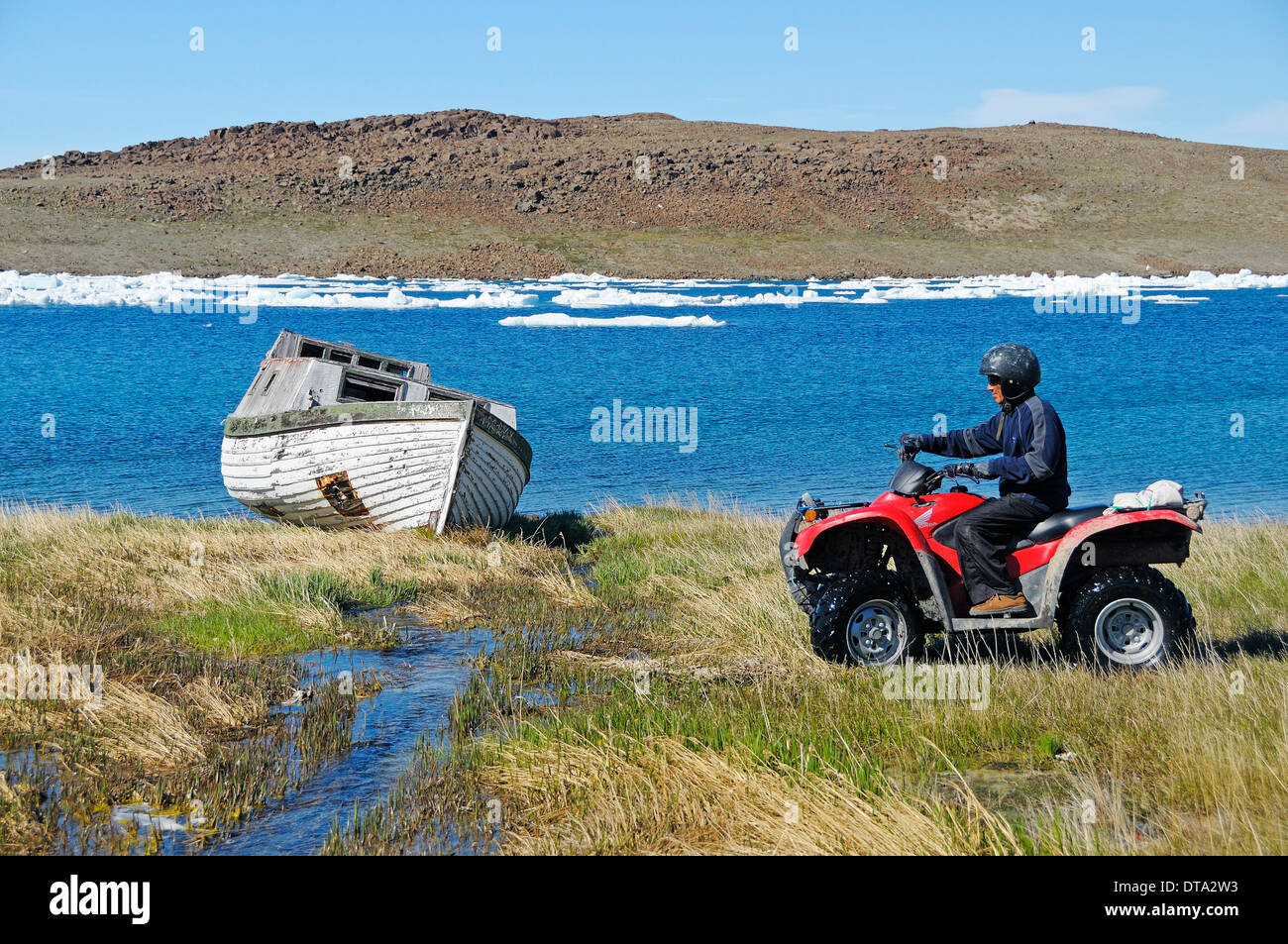 Man of the Inuit people riding a quad bike, ATM, in the tundra to Victoria Island, formerly Holman Island, village of Ulukhaktok Stock Photo