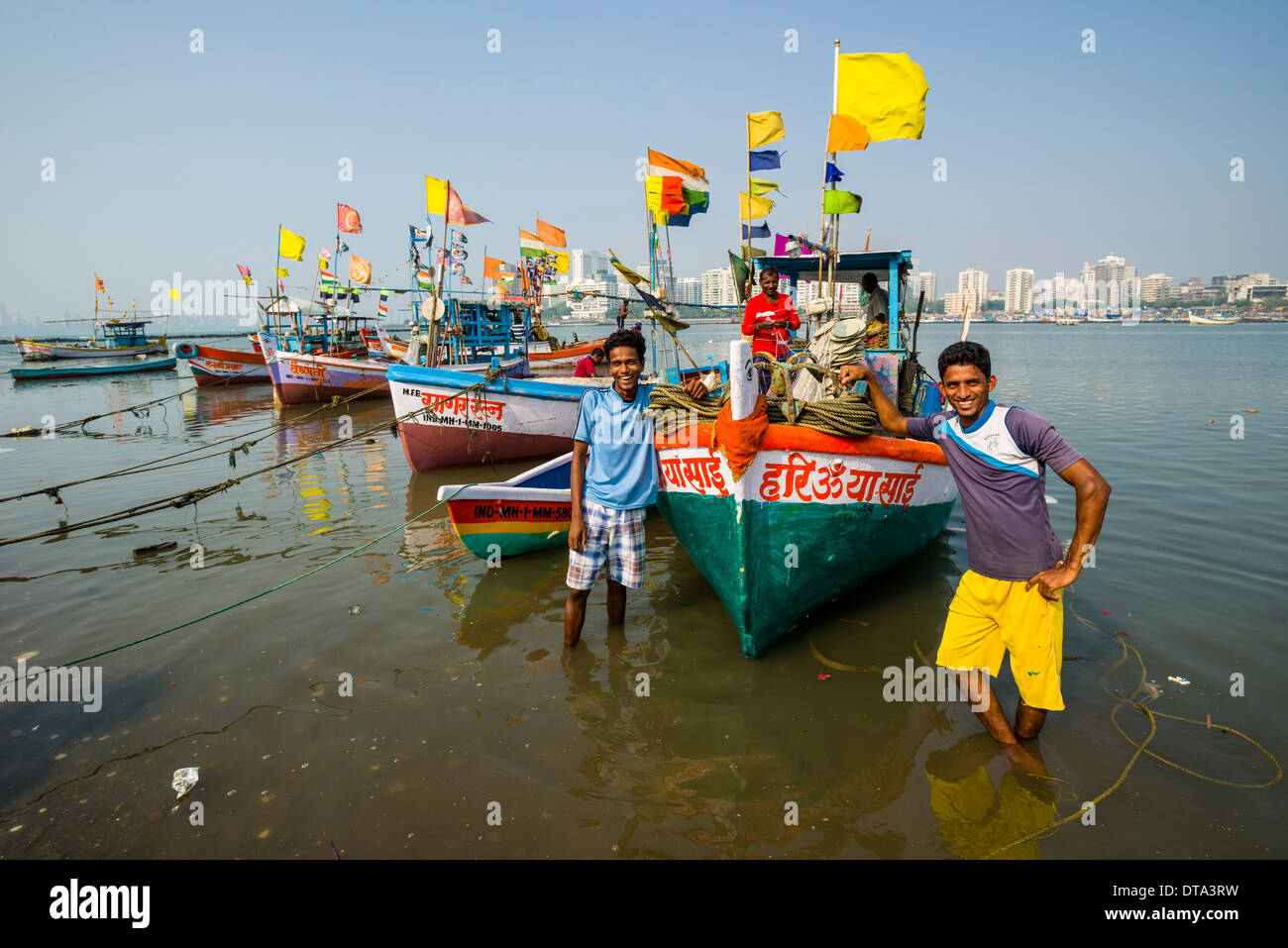Two fishermen and some fishing boats in front of the skyline of the suburb Churchgate seen across the Back Bay, Mumbai Stock Photo