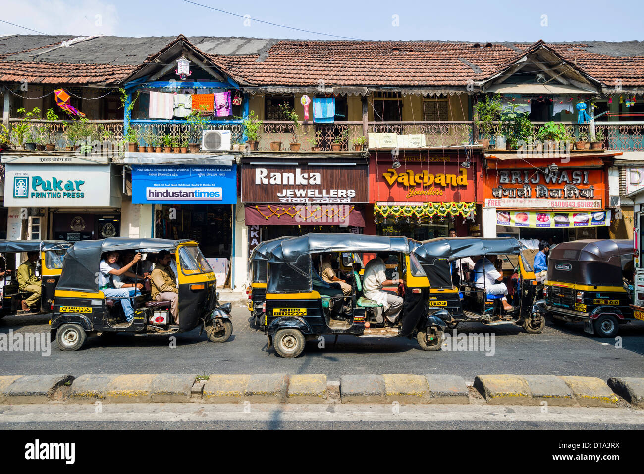 Motor rikshaws parked in front of a row of old houses, Bandra, Mumbai, Maharashtra, India Stock Photo