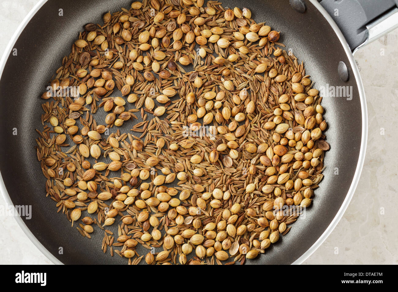 Cumin and Coriander Seeds roasted in small pan Stock Photo
