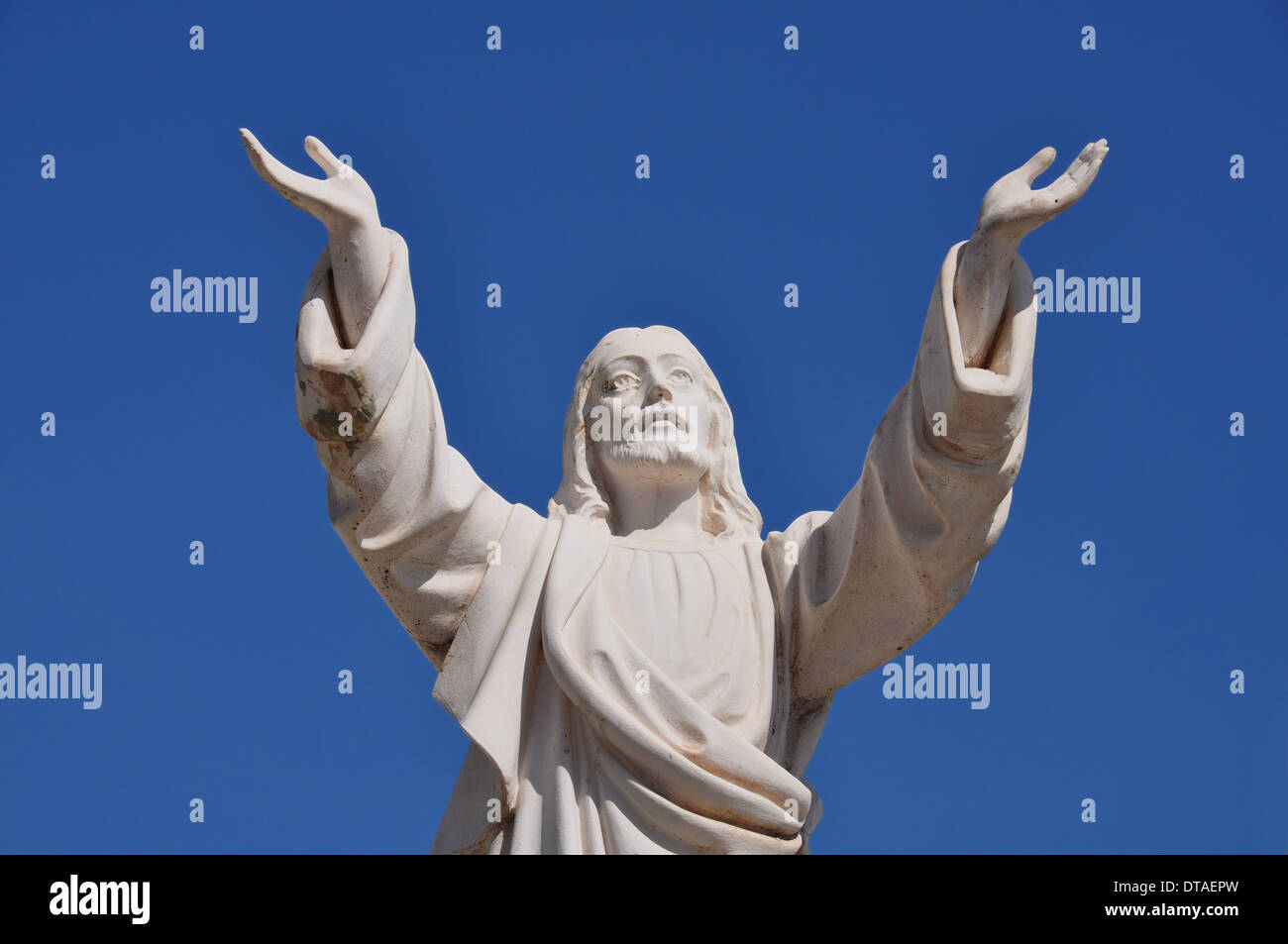 Jesus Christ with hands raised in blessing under blue sky. Marble funerary statue. Stock Photo