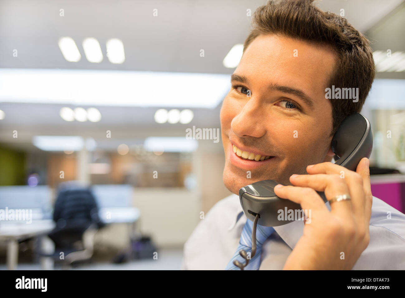 Smiling Businessman on phone in office, looking camera Stock Photo