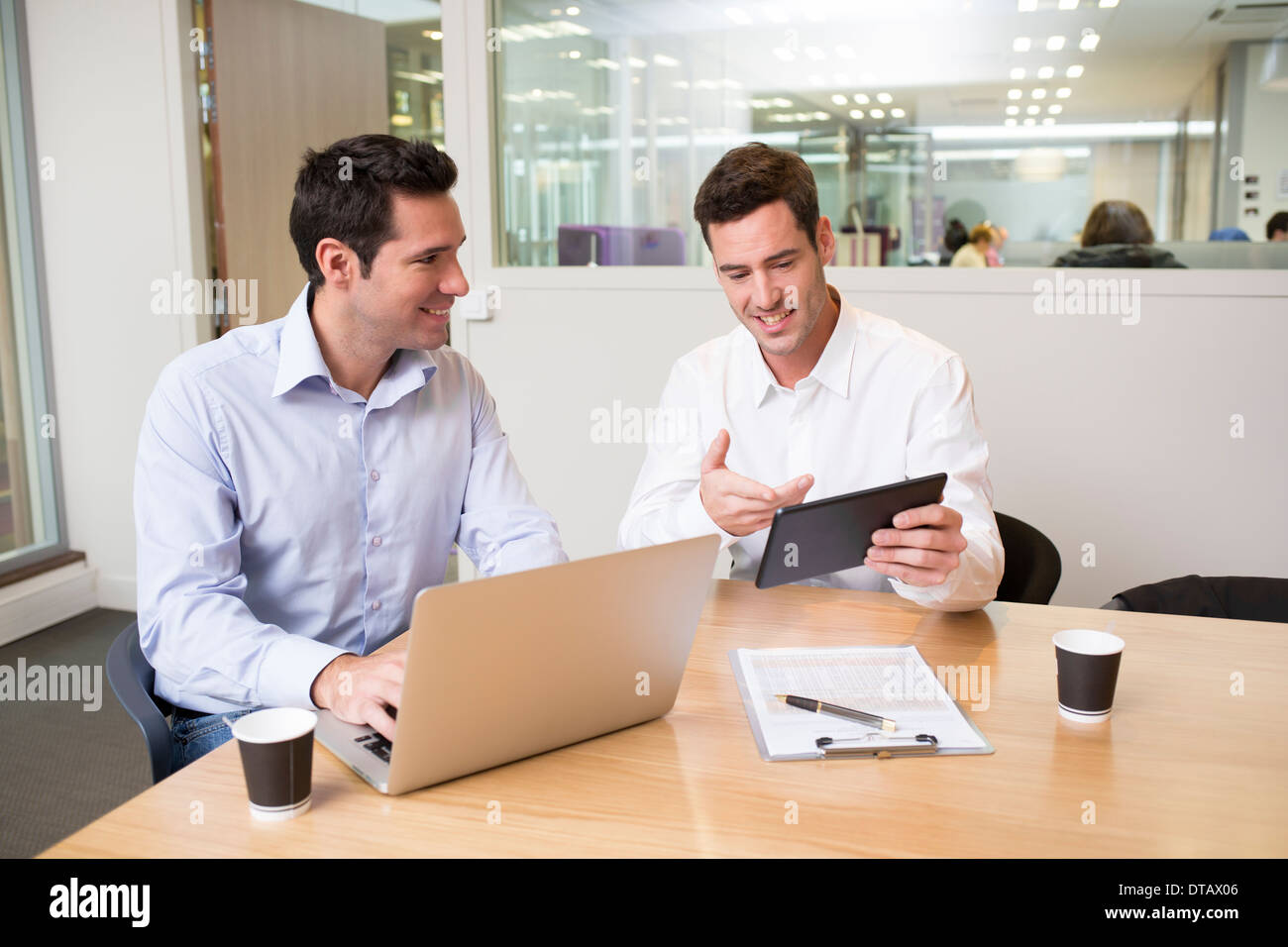Two casual businessmen working together in office with laptop and tablet pc Stock Photo
