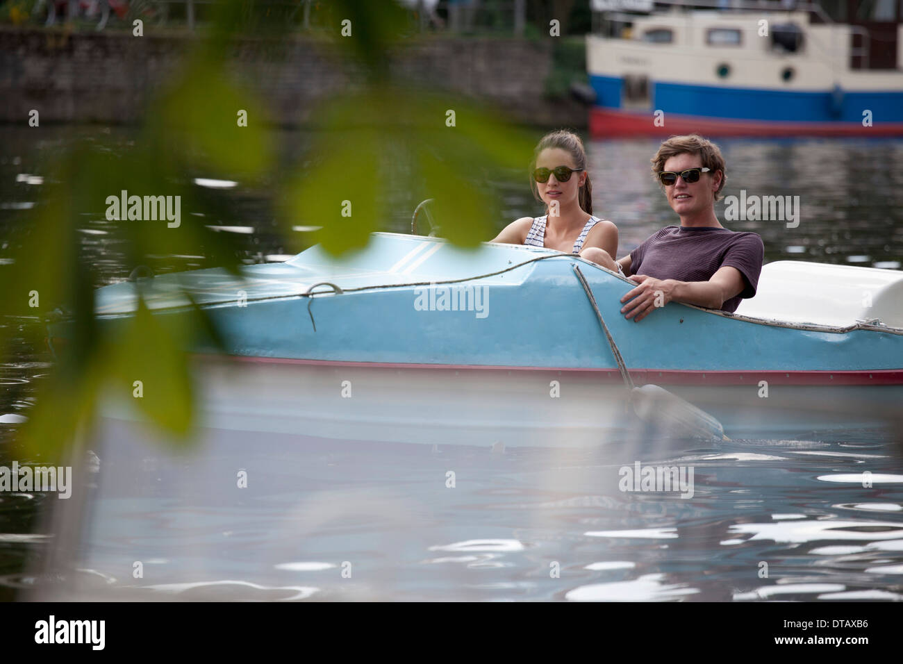 Young couple riding paddle boat on lake Stock Photo