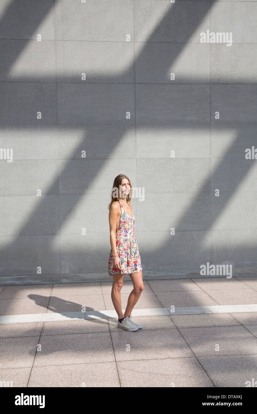 Young woman standing on pavement, looking away Stock Photo