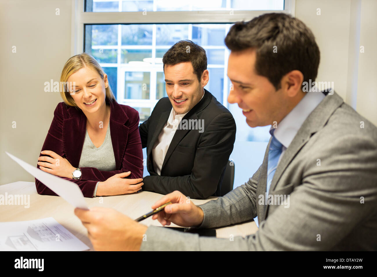 Businessman showing contract at young couple, new property owners Stock Photo
