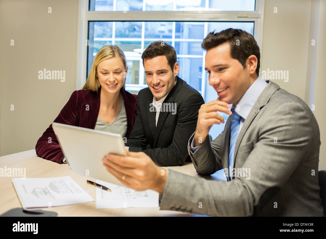 Architect showing a construction project on tablet at young couple, new property owners Stock Photo