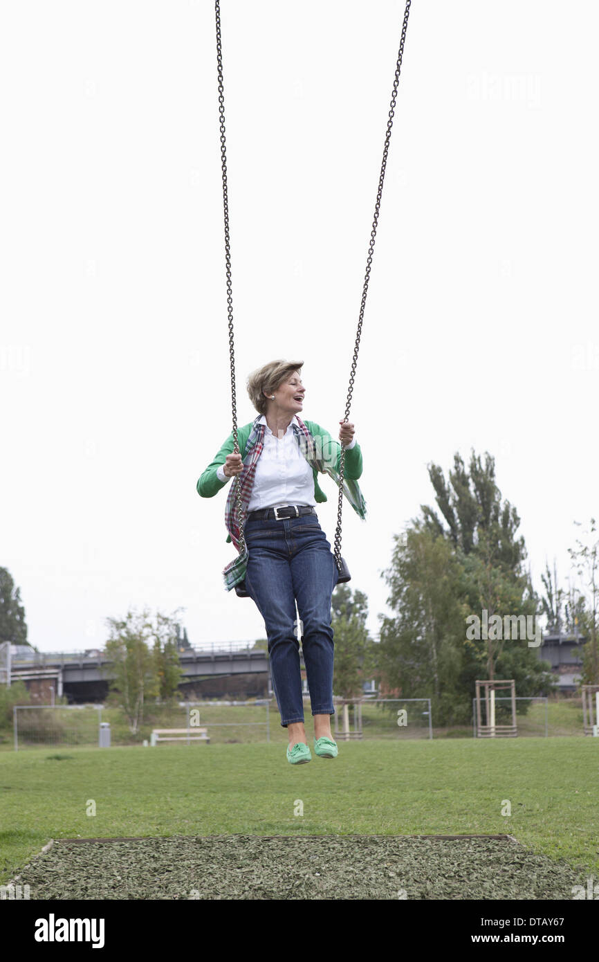 Mature woman swinging in park Stock Photo