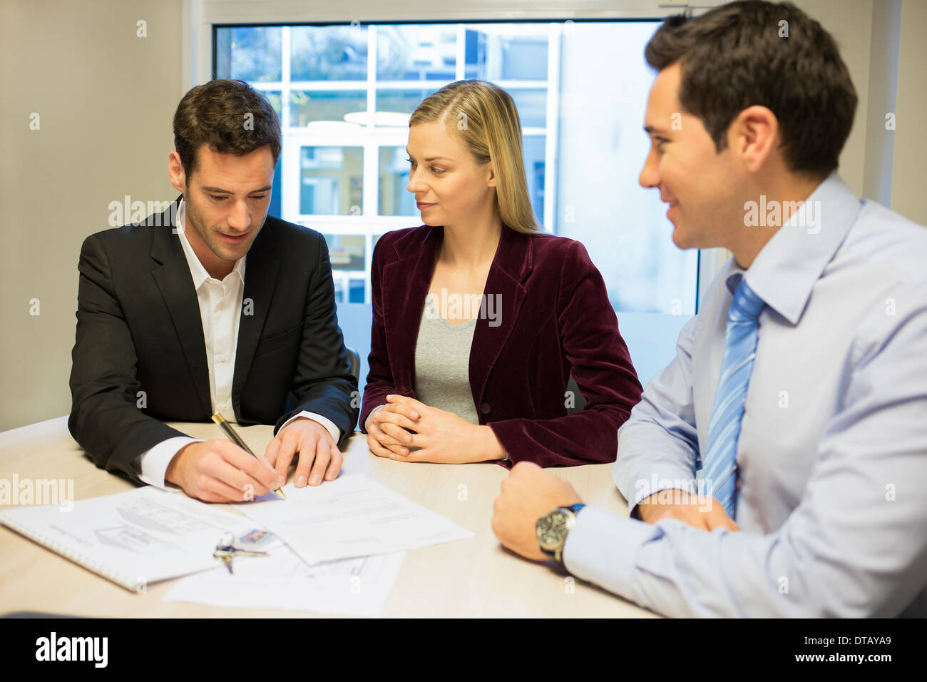 Young couple signing contract in office withe real-estate, new property owners Stock Photo
