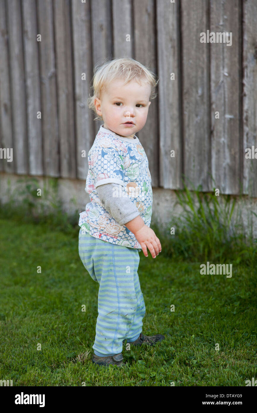 Baby boy standing on grass and looking away Stock Photo