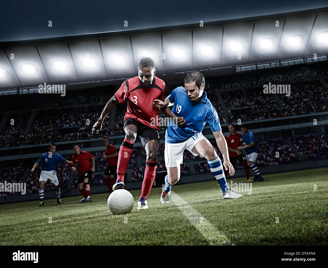 Soccer players chasing ball on field Stock Photo