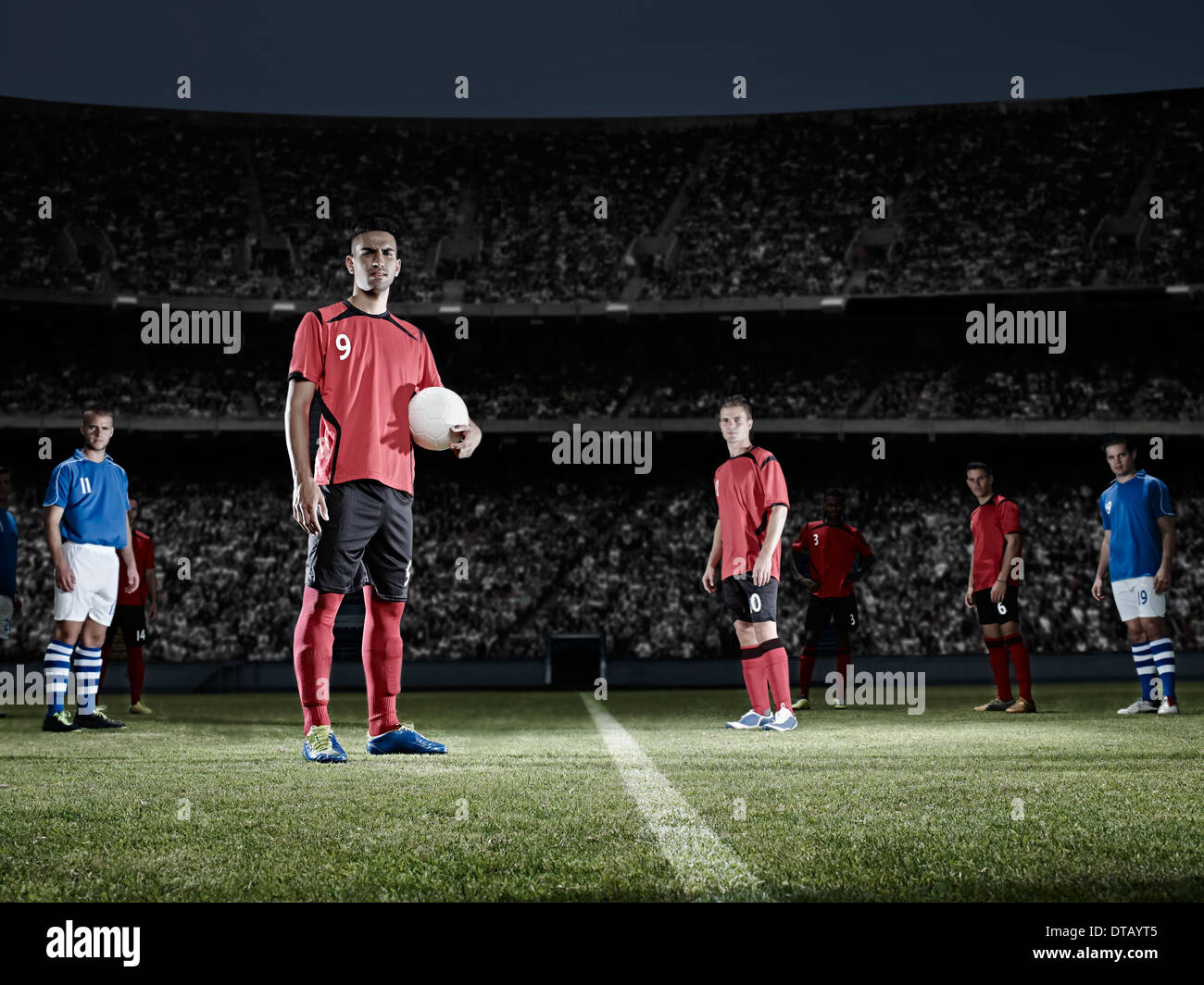 Soccer player holding ball on field Stock Photo