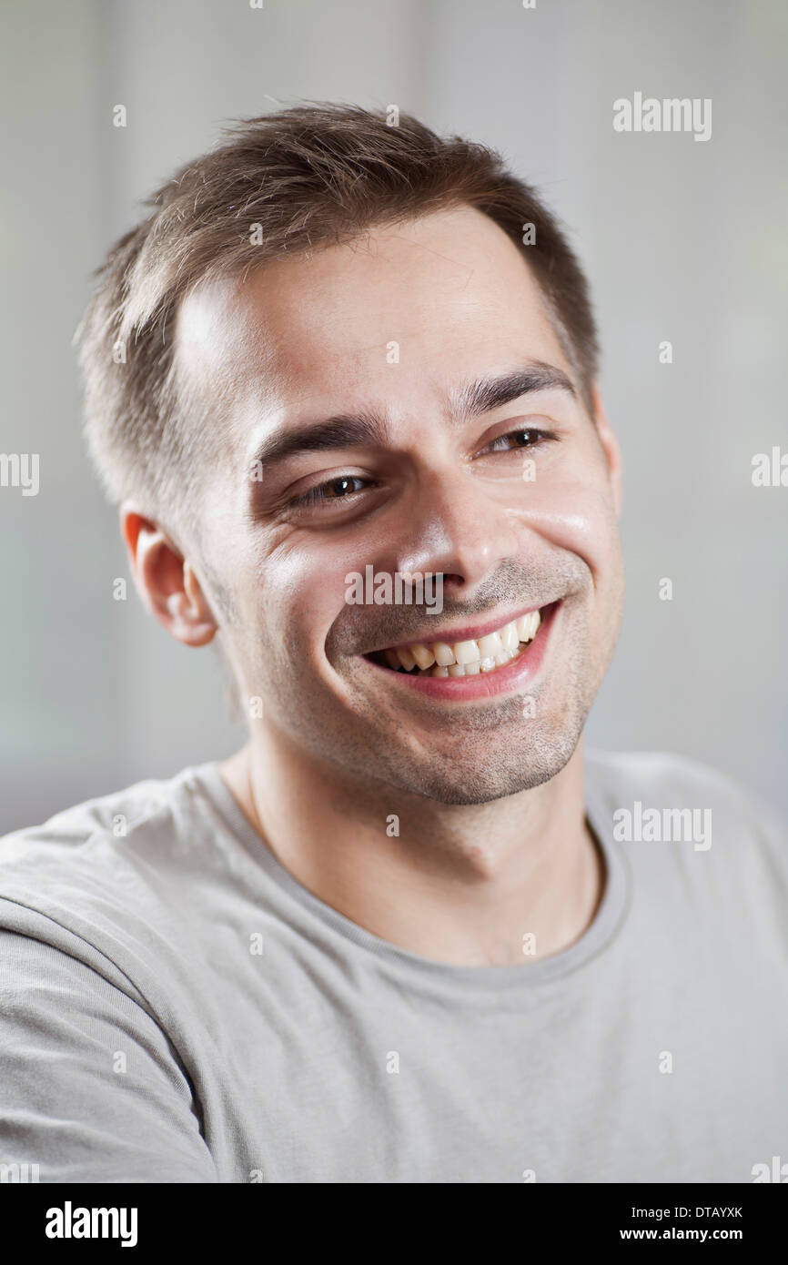 Young man looking away and smiling, close-up Stock Photo