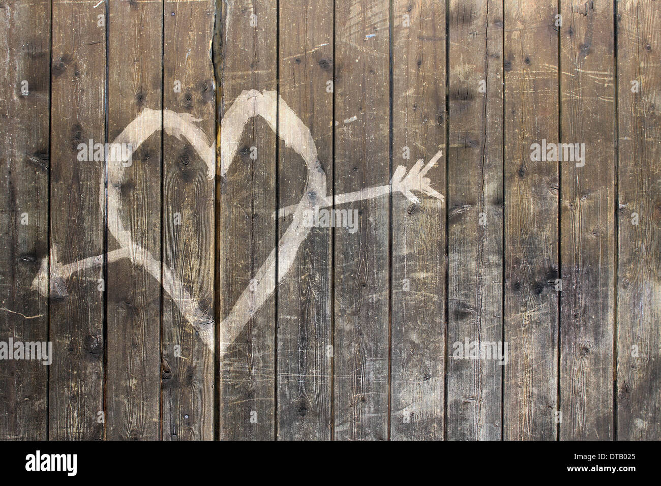 Heart shape with arrow symbol on wooden fence Stock Photo