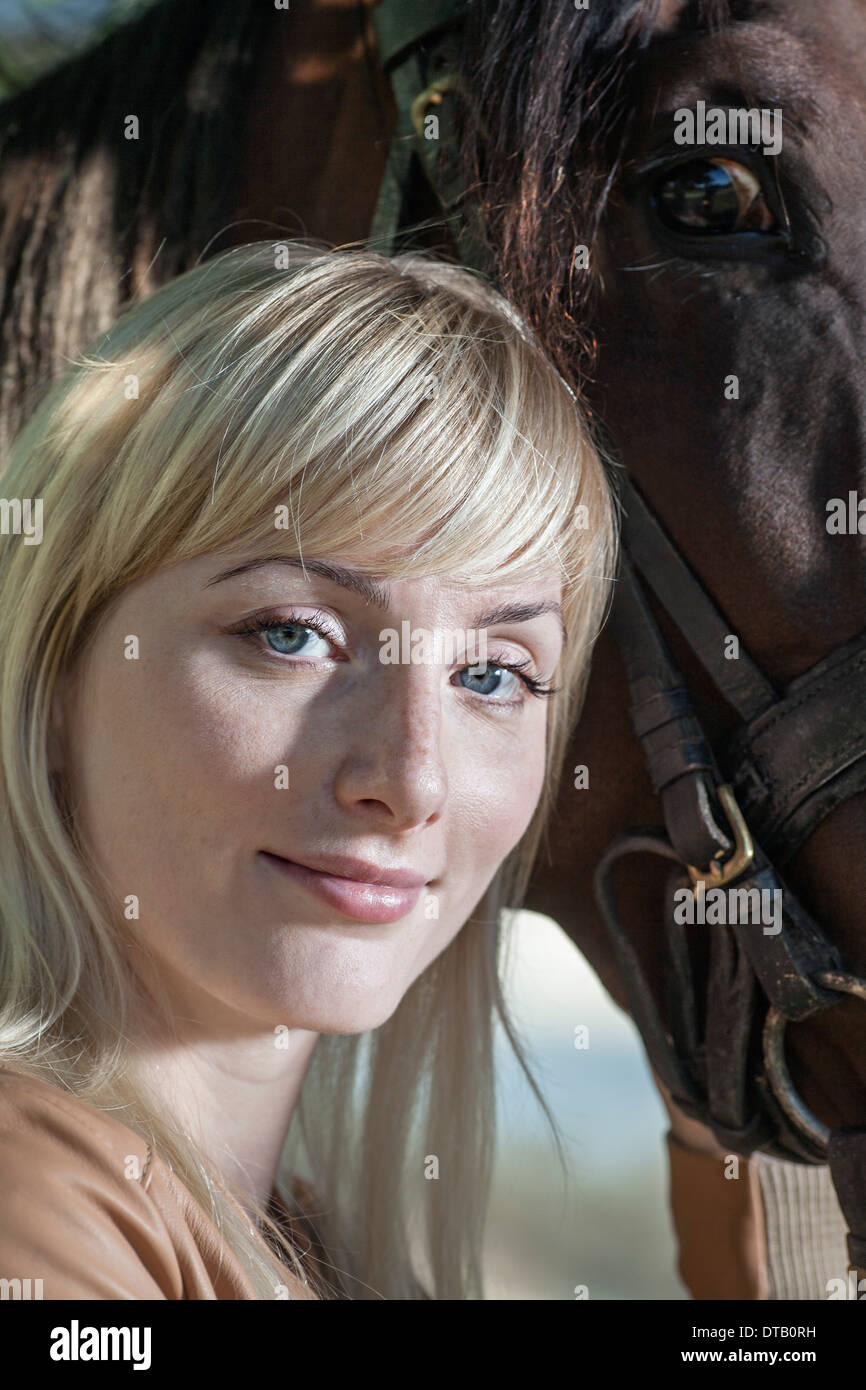 Portrait of young woman with horse, smiling Stock Photo
